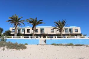 a large house on the beach with palm trees at Maravilla Bungalows in Cotillo