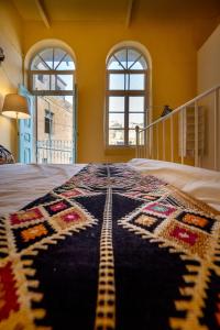 a bedroom with a blanket on a bed with two windows at Jordan Heritage Madhafa in Al Salt