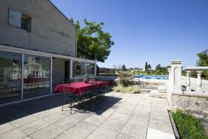 eine Terrasse mit einem roten Tisch und Stühlen neben einem Gebäude in der Unterkunft Villa de 3 chambres avec piscine privee jardin amenage et wifi a La Tour d'Aigues in La Tour-dʼAigues