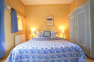 a bedroom with a blue and white bed with two lamps at La Colombiere du Château in Saint-Laurent-du-Verdon