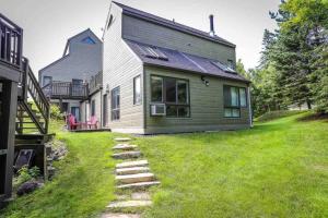 a house with a grass yard next to a house at The MountainSide by Escapades Tremblant in Mont-Tremblant