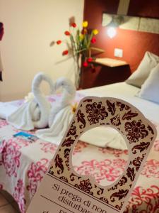 a sign on a bed with two swans on it at Rosa dei Venti Accomodation in Tropea