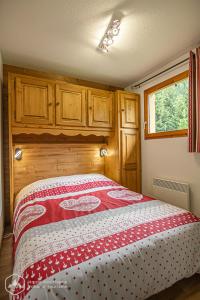 Schlafzimmer mit einem Bett mit einer roten und weißen Decke in der Unterkunft Chalets D'Arrondaz in Valfréjus