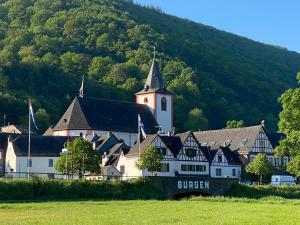 a large white building with a church in front of a hill at Ferienhaus am Baybach in Burgen an der Mosel in Burgen