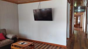 a living room with a couch and a tv on a wall at Cabañas Típicas ARIAS in Oxapampa