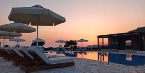 a swimming pool with lounge chairs and umbrellas at Tramonto Suites in Xi
