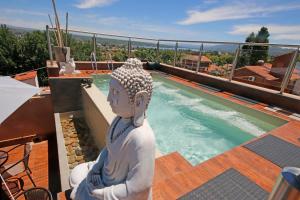a statue sitting on a deck next to a swimming pool at Rincón de Paz Apart & Loft Suite Boutique - Adults Only in Villa Carlos Paz