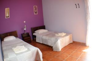 two beds in a room with purple walls at Ithaki House in Vathi