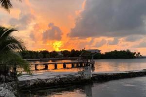 a sunset over a dock on a body of water at Keys Oceanfront Beauty Dock and pool in Marathon