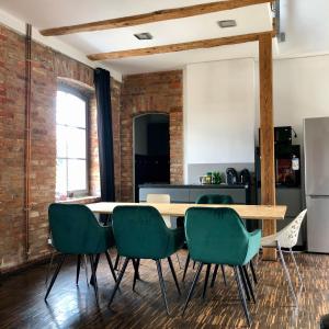 a kitchen with a wooden table and green chairs at Apartamenty Stara Winiarnia in Wałcz