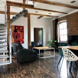 a room with chairs and a table and a tv at Apartamenty Stara Winiarnia in Wałcz