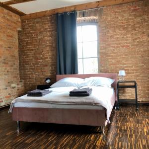 a bedroom with a large bed with a brick wall at Apartamenty Stara Winiarnia in Wałcz