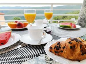 a table with plates of food and glasses of orange juice at Lovely apartment Branko Rabac with balcony and parking in Rabac +42 photos