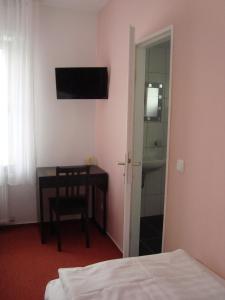 1 dormitorio con escritorio y mesa con silla en Hotel Gartenhof, en Mühlheim am Main