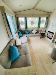 a large couch in a living room with blue pillows at 5 mins walk to beach. 3 bedroom caravan. Sleeps 8 in Clacton-on-Sea