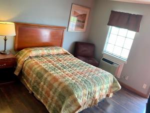 una camera con un letto e una sedia e una finestra di HiWay Inn Express a Elk City