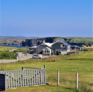 a house in a field with a fence at Salmon Landings in Strathy Point