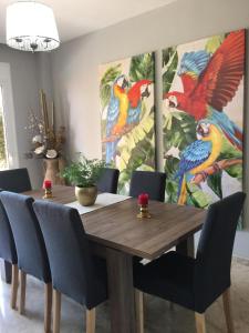 een eettafel met stoelen en een schilderij van vogels bij Apartamento de lujo en puerto santiago 2 in Puerto de Santiago