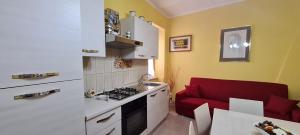 Una cocina con un sofá rojo y una cocina con estufa. en Casa La stella, en Pulcherini 34 fotos más