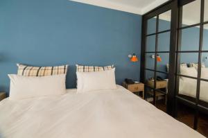 a bedroom with a large white bed with blue walls at 朵兒dor韓國汗蒸幕 동대문점 商務旅店 in Taipei