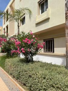 a building with pink flowers in front of it at Agréable Appartement avec piscine in Saïdia