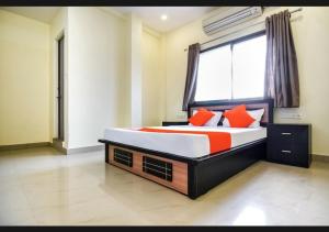 een slaapkamer met een bed met oranje kussens en een raam bij Silver Key Suites in Nagpur