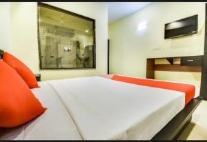 1 dormitorio con 1 cama grande con almohadas de color naranja en Silver Key Suites, en Nagpur