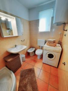 a bathroom with a sink and a toilet and a washing machine at House Vedran in Labin