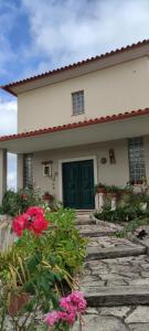 a house with a green door and some pink flowers at Beco do Patalugo in Salir de Matos