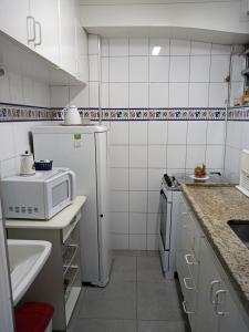 uma pequena cozinha com um micro-ondas e um frigorífico em Rota 013 - Santos Canal 4 em Santos