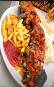 a plate of food with a piece of meat and french fries at Presken Hotels @ Victoria Island in Apese
