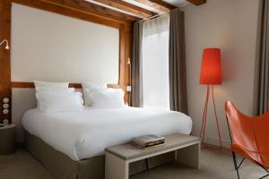 a bedroom with a large white bed and a red lamp at Relais & Châteaux La Maison Des Têtes in Colmar +61 photos