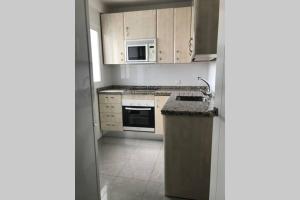 Una cocina con gabinetes blancos y un fregadero y microondas. en AC TRIANA numancia, en Sevilla