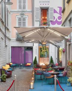 un patio con tavoli, sedie e ombrellone di 73 Boutique Hotel a Como