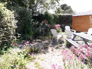 two chairs and a picnic table in a garden with flowers at Le cottage normand in Saint-James