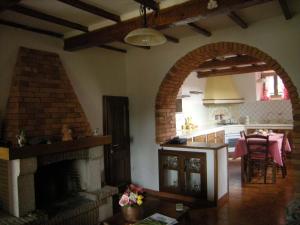 a living room with a brick fireplace and a kitchen at Casa Elisa in Bibbiena