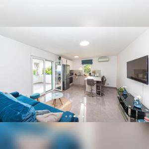 a living room with a blue couch and a kitchen at Holiday home Petra - house with a sea view in an isolated location in Vinišće