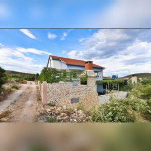 a house with a stone wall next to a dirt road at Holiday home Petra in Vinišće