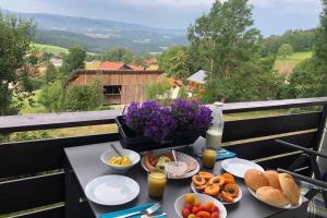 a table with breakfast food on a balcony at Apartment Tälerblick in Böbrach