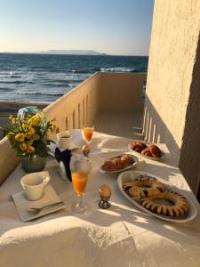 a table with food and drinks on a balcony with the ocean at Anthoula Apartments in Kokkíni Khánion