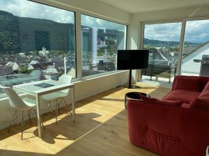 Weingut-Aparthotel Olinger في ميهرينغ: غرفة معيشة مع أريكة حمراء وتلفزيون
