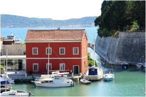 a red building with boats docked in a harbor at Apartments Villa Violet in Zadar