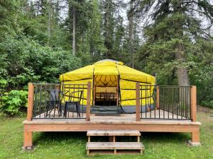 um gazebo com uma tenda amarela num deque de madeira em Whitetail Creek Camping Resort em Lead