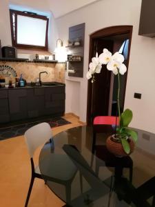 a kitchen with a glass table and a vase with white flowers at La perla nel pozzo in Orvieto