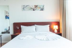 um quarto com uma cama branca e uma cabeceira em madeira em Pauraque Soho Hotel em Dar es Salaam