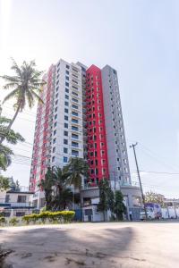 a tall red and white apartment building with palm trees at Pauraque Soho Hotel in Dar es Salaam