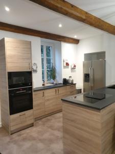 une cuisine avec des placards en bois et un comptoir noir dans l'établissement LE GITE DU CARGE D'ARLAY, à Charnay-lès-Mâcon