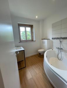 La salle de bains blanche est pourvue d'une baignoire et de toilettes. dans l'établissement LE GITE DU CARGE D'ARLAY, à Charnay-lès-Mâcon