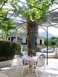 a table with chairs and an umbrella on a patio at Villa Ban in Podgora