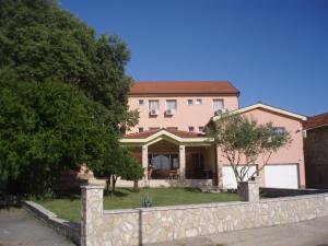 a large pink house with a stone fence at Hotel ''Marinko Kozina'' - Medjugorje in Međugorje